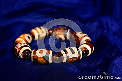 Bracelet : Tibetan Dzi beads bracelet, on blue background. Dzi bead is considered to provide positive spiritual benefit. These Stock Photo