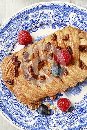 Braided danish bun made of puff pastry decorated with fresh fruits Stock Photo