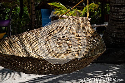 Braided hammock in palm leaf shadow on beach. Empty hammock of abandoned luxury resort Stock Photo