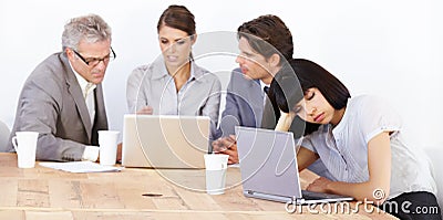 Brainstorming is exhausting. Three executives brainstorming while an exhausted colleague sleeps next to them. Stock Photo