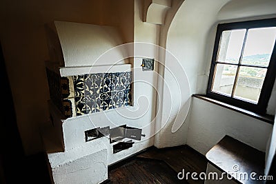 Bran, Brasov, Romania- June, 2023: Cozy interior view showcasing a traditional European tiled stove next to a window with Editorial Stock Photo
