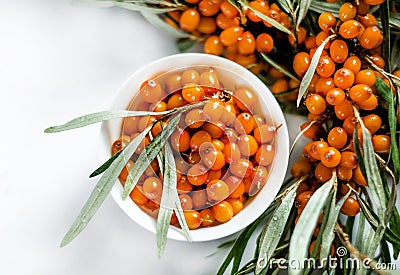 Branch of sea buckthorn with oil on wooden texture background Stock Photo