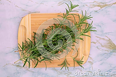 Branches of fresh rosemary on a wooden board. View from above. Stock Photo