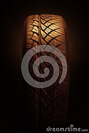 Brand new modern car tyre on a black background. Studio shot Stock Photo