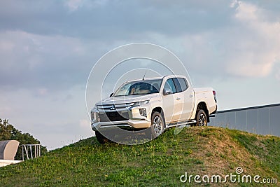 Brand new white Mitsubishi L200 pickup presented by dealership on an artificial hill to promote the automotive brand Editorial Stock Photo