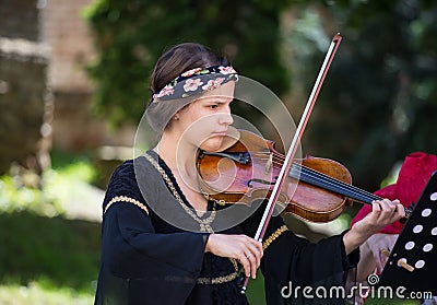 Brasov Romania-June 14 2018 : Beautiful girl violinist playing national Romanian music on the background of Brasov Editorial Stock Photo