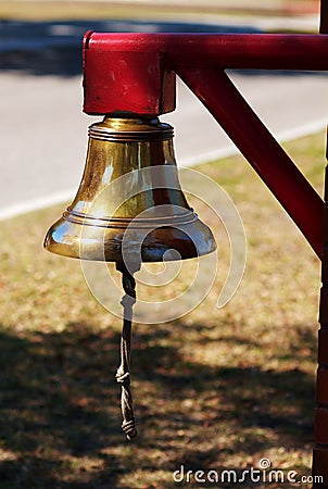 Brass bell hanging from red post Stock Photo