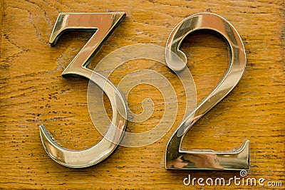 Brass number thirty two on wall Stock Photo