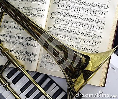 Brass Trombone and classical music laid over synthesizer keyboard. Stock Photo