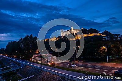 Bratislava castle illuminated in evening glow against dramatic sky Editorial Stock Photo