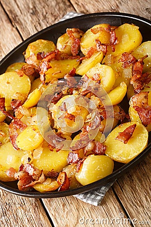 Bratkartoffeln German Cottage Potatoes With Bacon and Onion close up in the plate. Vertical Stock Photo