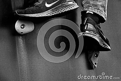 Feet in sneakers support on climbing wall and push athlete up, concept image for climb and effort, black and white Editorial Stock Photo