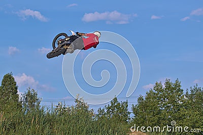 A brave biker jumps very high on a motorcycle and performs a stunt. Editorial Stock Photo