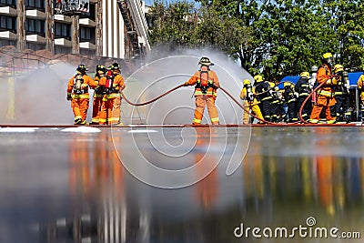 Brave firefighter using extinguisher and water from hose for fire fighting, Firefighter spraying high pressure water to fire, Editorial Stock Photo