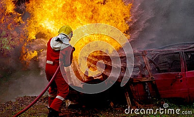 Brave firefighter using extinguisher and water from hose for fire fighting, Firefighter spraying high pressure water to fire, Stock Photo