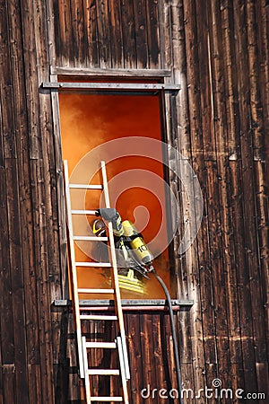 brave firefighters with oxygen cylinder goes into a house through a window during a fire Stock Photo