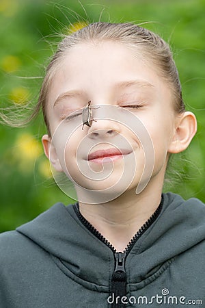 Cockchafer sits on the girl`s face Stock Photo