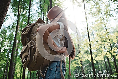 Hipster girl traveling alone and looking around in forest on outdoors wearing treveler backpack and hold location map in han Stock Photo