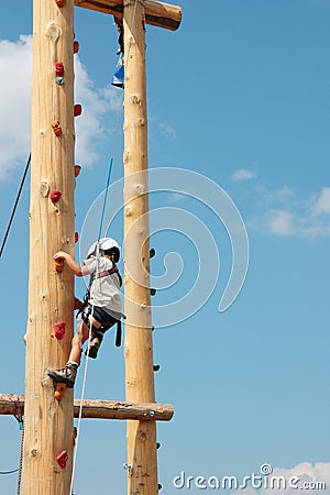 Brave little boy climbing up on a wooden pole for children climbing exercises Stock Photo