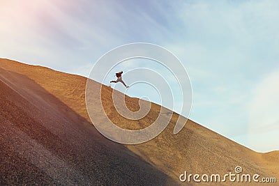 Brave man with backpack running and jumping on a dune Stock Photo