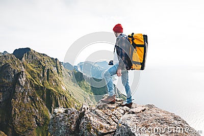 Brave man tourist with backpack standing on the edge mountain above sea and looking forward away Stock Photo