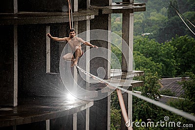 Brave topless man balancing on a slackline on rainy day Stock Photo