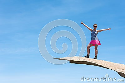 Brave young adult woman hiker stands on top of Potato Chip Rock in San Diego California Stock Photo