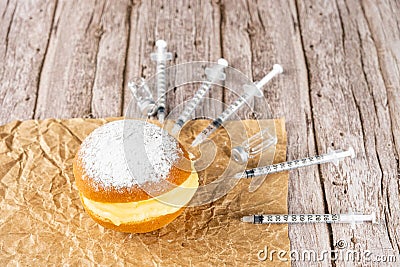Brazilian cream donuts on a brown paper and surrounded by several syringes and ampoules of insulin Stock Photo