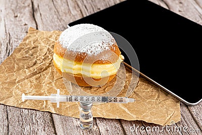 Brazilian cream doughnuts next to a syringe over an insulin ampoule and a tablet Stock Photo