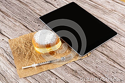 Brazilian cream doughnuts next to a syringe taking insulin from an ampoule and a tablet Stock Photo