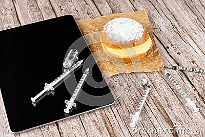 Brazilian cream doughnuts surrounded by various syringes and ampoules with insulin and a tablet Stock Photo