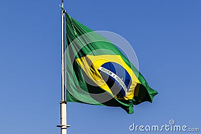 Brazilian flag flutters on a flagpole with the blue sky Stock Photo