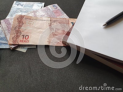 Brazilian money, books and pen on black background Stock Photo