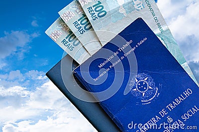 Brazilian Work Card with Brazilian money isolated on blue sky and clouds background. Written in Portuguese Federative Republic of Stock Photo