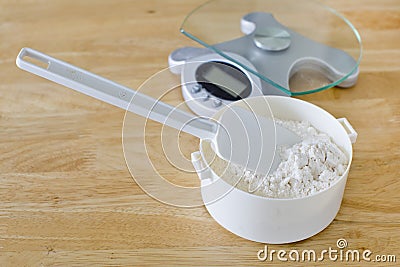 Bread flour in white bowl with rubber scraper and scale on wood Stock Photo