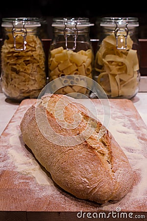 Bread laid on a chopping board, with pasta bowls in the backgrou Stock Photo