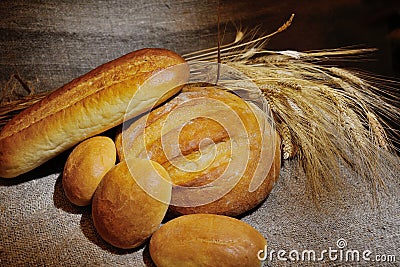 Bread, loaf, white bread, wheat ears on a background of burlap Stock Photo
