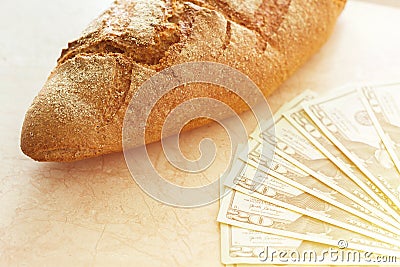 Bread near a pack of banknotes, 100 dollar bills spread out like a fan, composition. Stock Photo