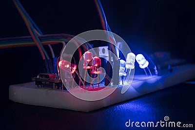 Breadboard arduino nano prototyping board transistors resistors LEDs red and blue in glow in the dark on black skin Stock Photo