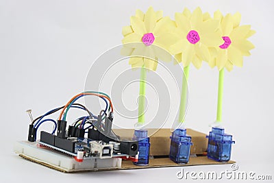 Breadboard circuit with programmable controller board and micro servo with artificial flowers attached to horn of servos Stock Photo
