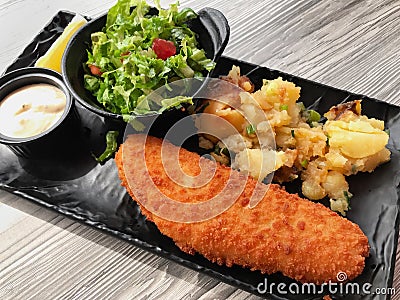 Breaded white fish with potatoes and fresh lettuce salad Stock Photo
