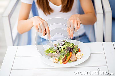 Break for energy, vitamins and refreshness. Close up cropped photo of lady, eating salad on a white modern wood table in an open Stock Photo