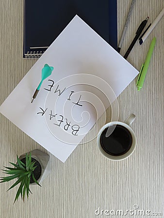 Break Time Concept. Relaxation. Office desk table with break time note, notebooks, supplies, flowers and coffee cup. Top view. Stock Photo