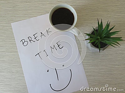 Worktable. Break Time Concept. Office desk table with break time note, coffee cup and flowers. Relaxation. Top view. Stock Photo