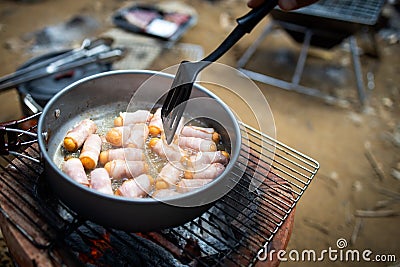 Breakfast for all ages,Pigs in Blankets or Mini sausages wrapped in smoked bacon on a hot frying pan on a charcoal grill at Stock Photo