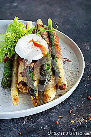 Breakfast of baked asparagus in spices with bacon, poached egg and crispy salad. Stock Photo