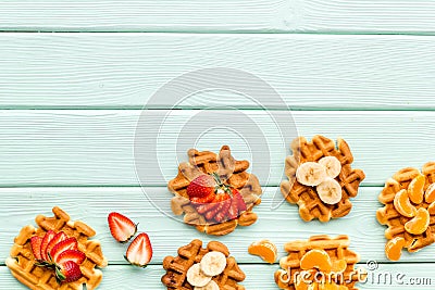 Breakfast with Belgian waffles with strawberry, tangerine and banana topings on mint green background top view mockup Stock Photo