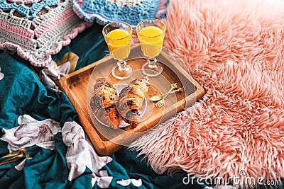 Breakfast brought to bed on a wooden tray. Orange juice in glasses and sweet croissants. Stock Photo