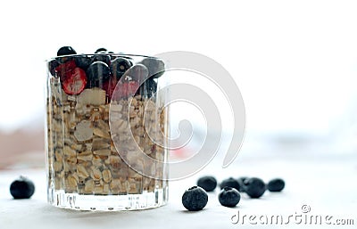 Close glass of granola oatmeal with chia, cranberry and american blueberries on table Stock Photo