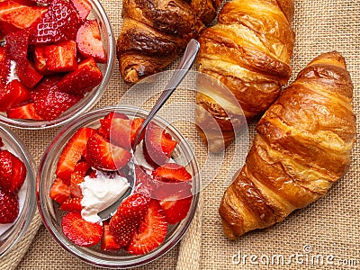 Breakfast with fresh croissants, strawberry with cream in glass bowls background Stock Photo